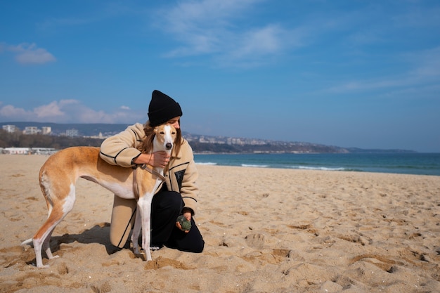 Perro galgo con dueña en la playa