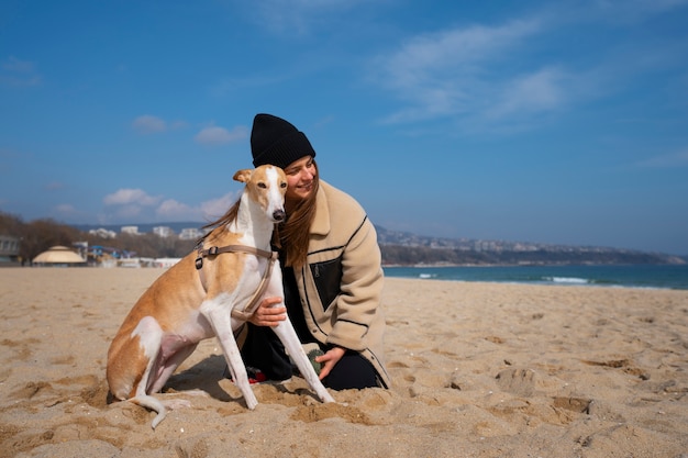 Foto gratuita perro galgo con dueña en la playa