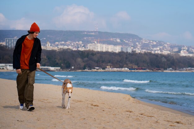 Perro galgo con dueño masculino en la playa