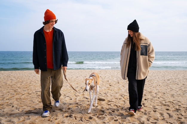 Foto gratuita perro galgo con dueños de pareja en la playa