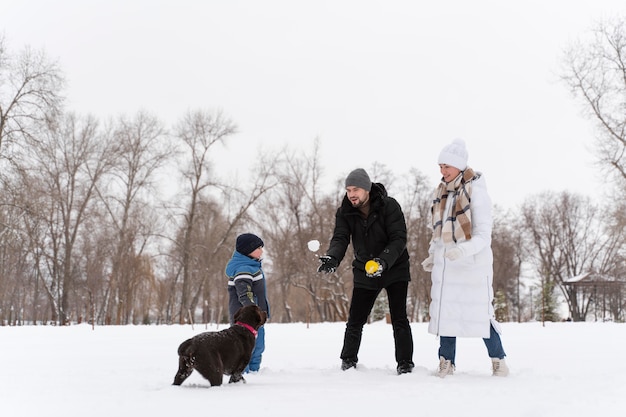 Perro jugando con niños en la nieve con la familia