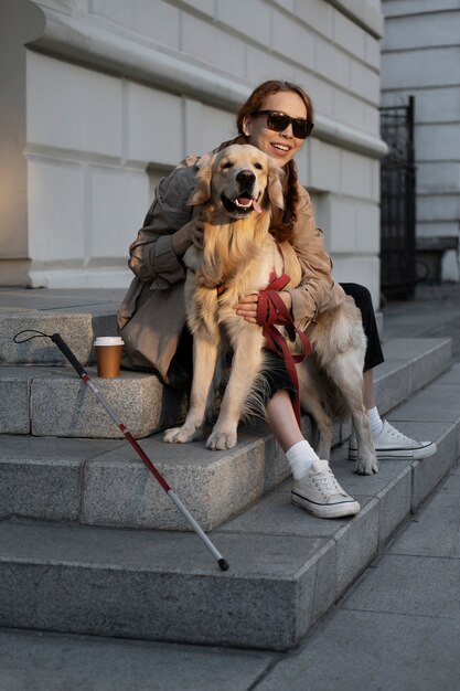 Perro de servicio de caricias de mujer sonriente de tiro completo