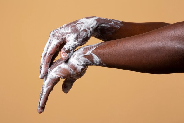 Persona africana lavándose las manos con jabón aislado en naranja