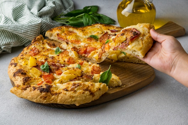 Foto gratuita persona agarrando una deliciosa rebanada de pizza