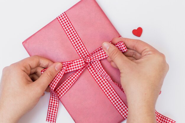 Persona atar arco en caja de regalo rosa grande