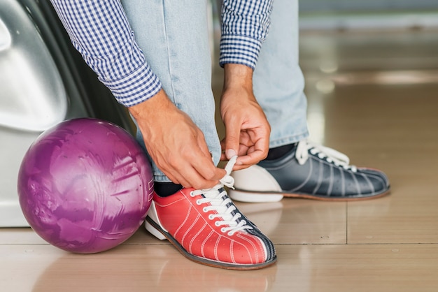 Persona atar cordones de zapatos y bola de boliche