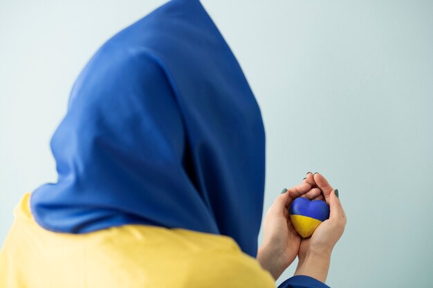 Persona con bandera ucraniana sosteniendo piedra pintada en azul y amarillo.