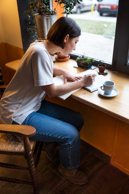 Foto gratuita persona en un café disfrutando de un libro