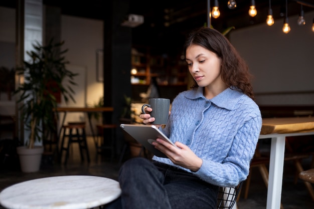 Foto gratuita persona en un café leyendo un libro mientras toma un café