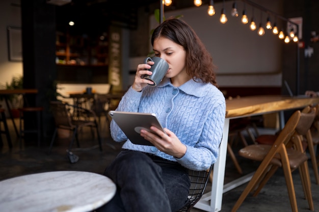 Foto gratuita persona en un café leyendo un libro mientras toma un café