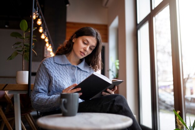 Persona en un café leyendo un libro mientras toma un café