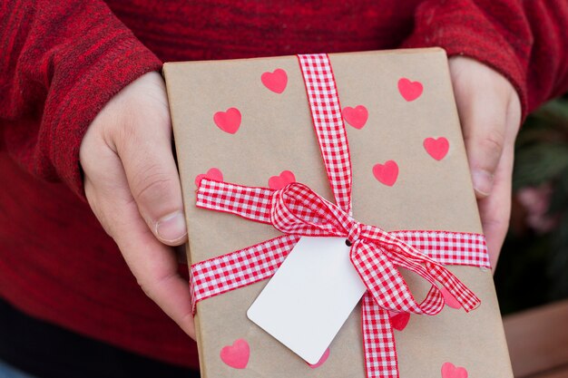 Persona con caja de regalo con corazones en las manos