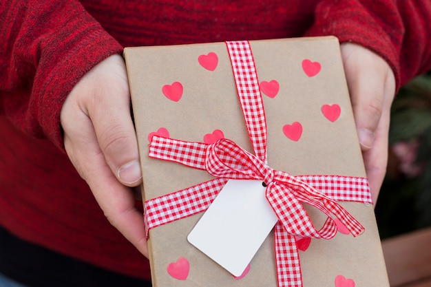 Persona con caja de regalo con corazones en las manos