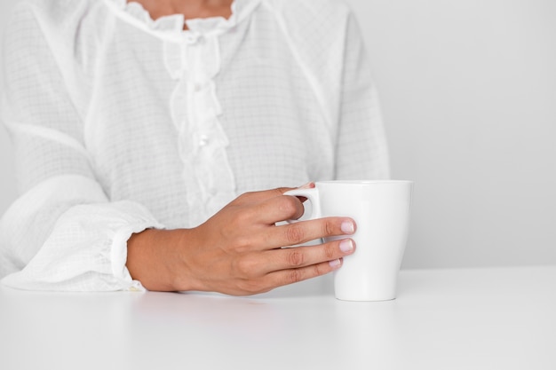 Foto gratuita persona en camisa blanca sosteniendo una taza