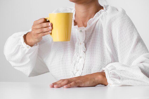 Persona en camisa blanca sosteniendo una taza