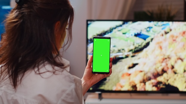 Foto gratuita persona caucásica sosteniendo verticalmente la pantalla verde en el teléfono inteligente