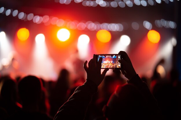 Persona cerca de la grabación de video con el teléfono inteligente durante un concierto