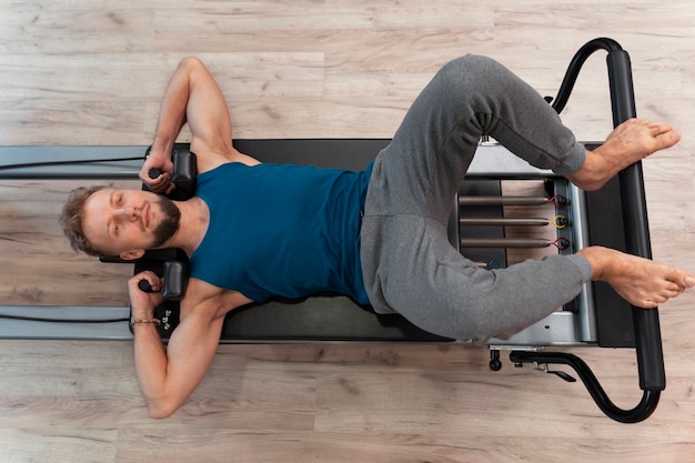 Foto gratuita persona en clase reformadora de pilates ejercitando su cuerpo