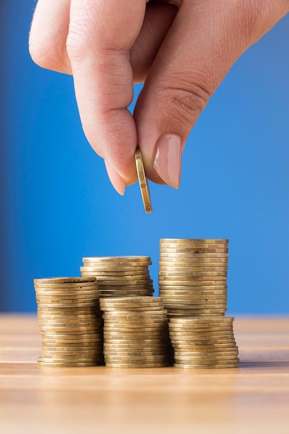 Persona colocando una moneda sobre un montón de monedas