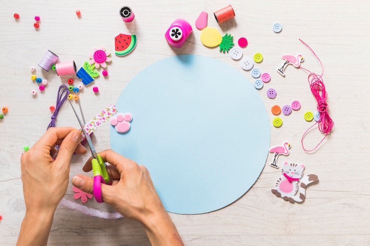 Foto gratuito una persona cortando cinta con tijera sobre el papel azul con elementos decorativos