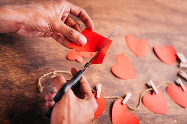 Persona cortando corazones de papel