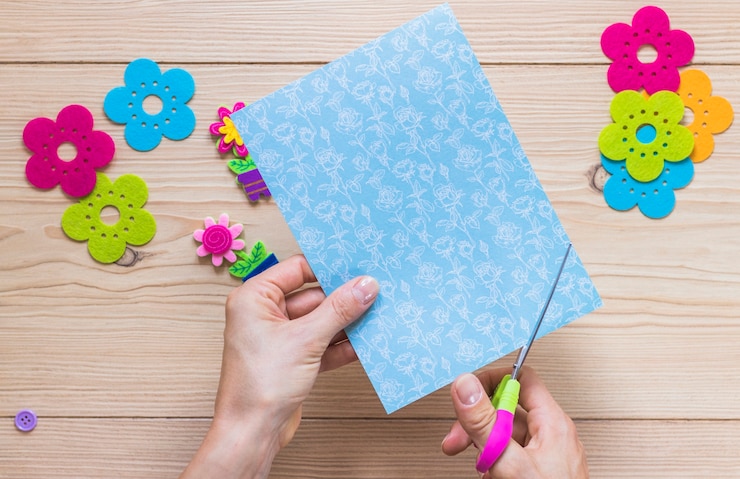Foto gratuito una persona cortando papel artesanal con tijera en la mesa