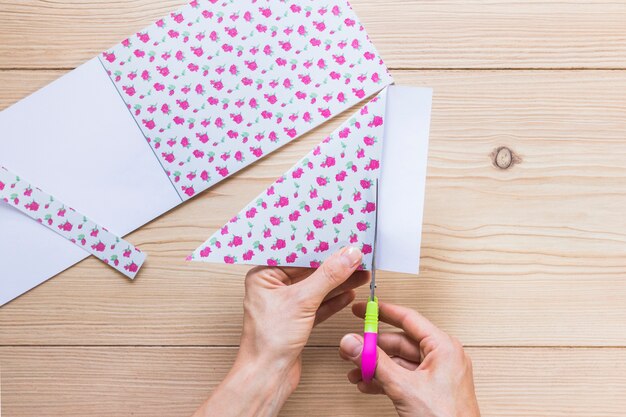 Una persona cortando papel floral con tijera sobre la mesa