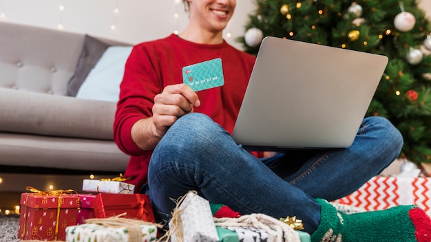 Persona de la cosecha con tarjeta usando laptop para ir de compras