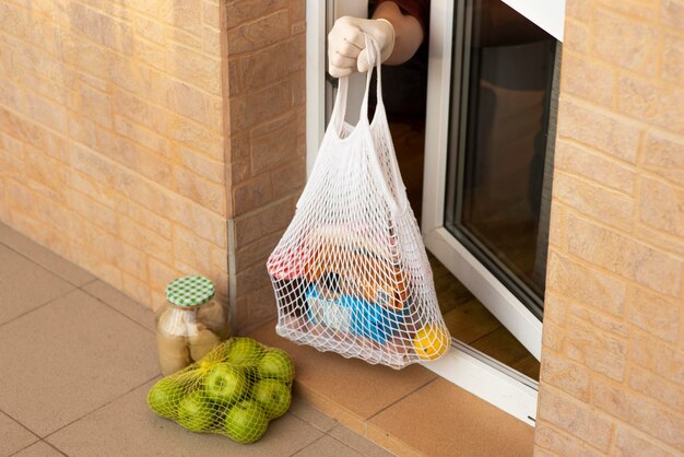 Persona en cuarentena tomando alimentos desde su puerta principal