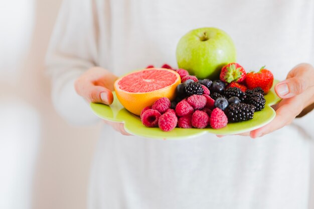 Persona de cultivo mostrando plato de fruta