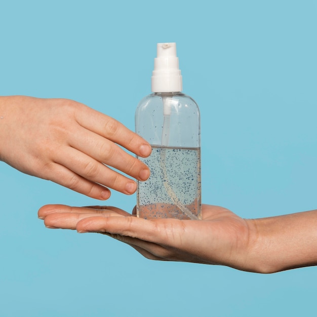 Foto gratuita persona desinfectando las manos aisladas en azul