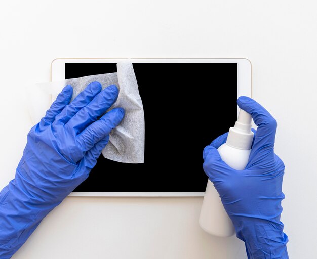 Foto gratuita persona desinfectando una tableta