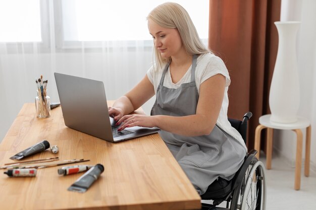 Persona discapacitada en silla de ruedas trabajando en equipo portátil