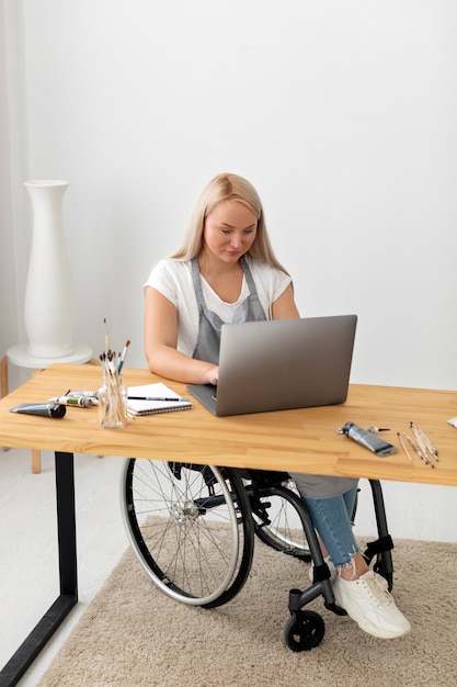 Foto gratuita persona discapacitada en silla de ruedas trabajando en equipo portátil