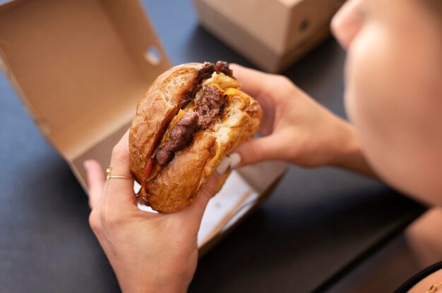 Persona disfrutando de una hamburguesa para llevar