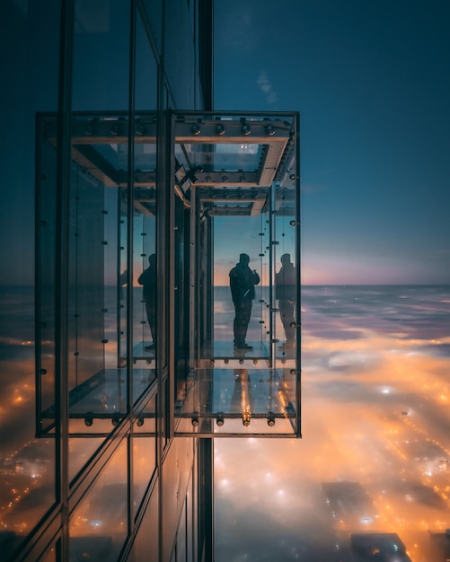 Persona disfrutando de la hermosa vista de la ciudad en un balcón con paredes de vidrio