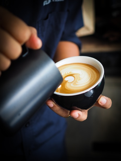 Persona echando leche a una taza de café