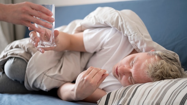 Persona enferma que recibe un vaso de agua