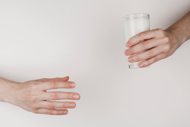 Una persona entregando un vaso de leche a otro