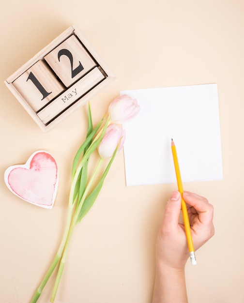 Persona escribiendo en papel cerca del 12 de mayo de inscripción.