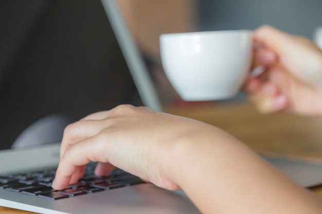 Persona escribiendo y sujetando una taza blanca