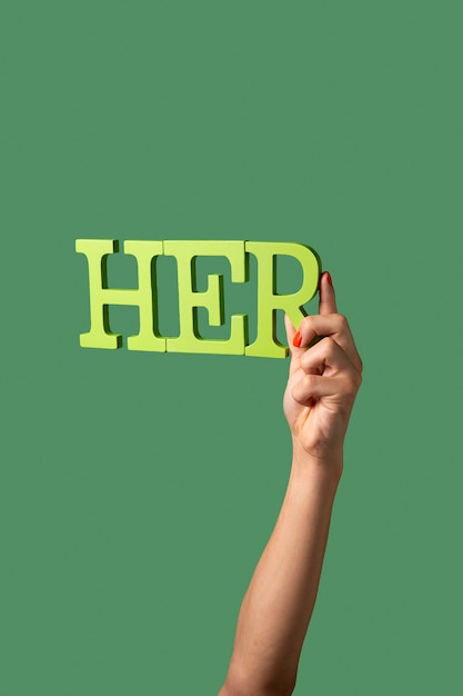Persona de género fluido sosteniendo un pronombre aislado en verde