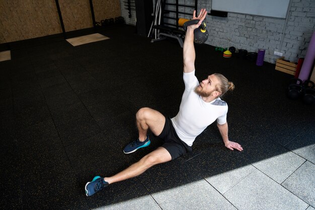 Persona en el gimnasio deportivo usando pesas rusas