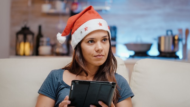 Persona con gorro de Papá Noel y trabajando en tableta digital