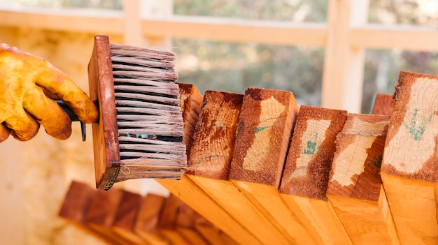 Persona con guantes de protección y barnizando la madera