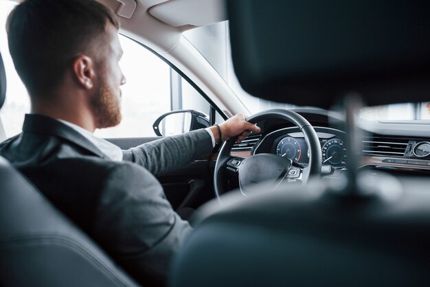 Una persona. Hombre de negocios moderno probando su nuevo coche en el salón del automóvil