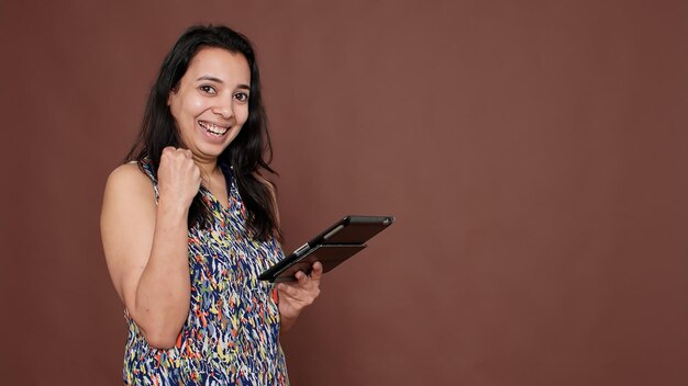 Persona india que usa una tableta digital para lograr el éxito, sintiéndose orgullosa mientras navega por la aplicación del sitio web de Internet. Dispositivo portátil con pantalla táctil para desplazarse por las redes sociales.