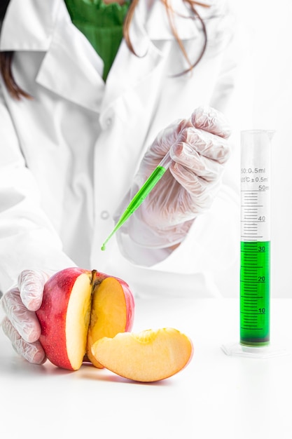 Persona inyectando una manzana con químicos verdes