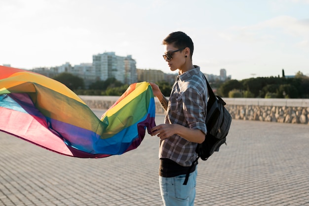 Persona joven con bandera LGBT volando.