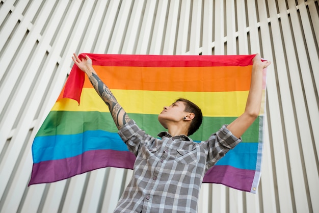 Persona joven que sostiene la bandera del arco iris